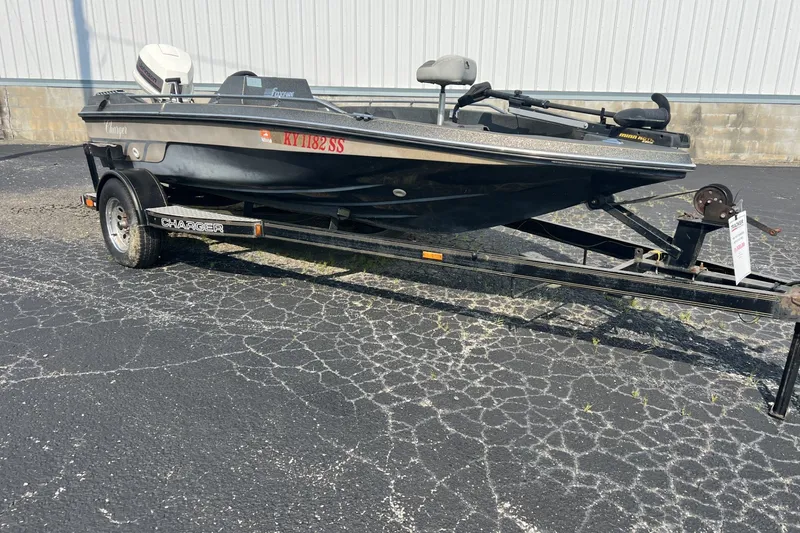 The Image of 1988 Charger 162V boat on trailer, parked on cracked asphalt surface. - 1