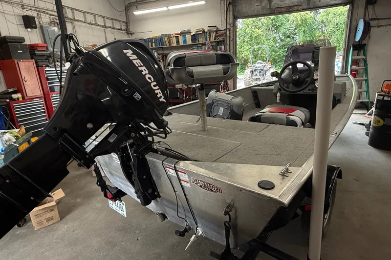 Slide: The Image of 2013 Bass Tracker Pro 16 boat with Mercury outboard motor in a garage setting. - 14