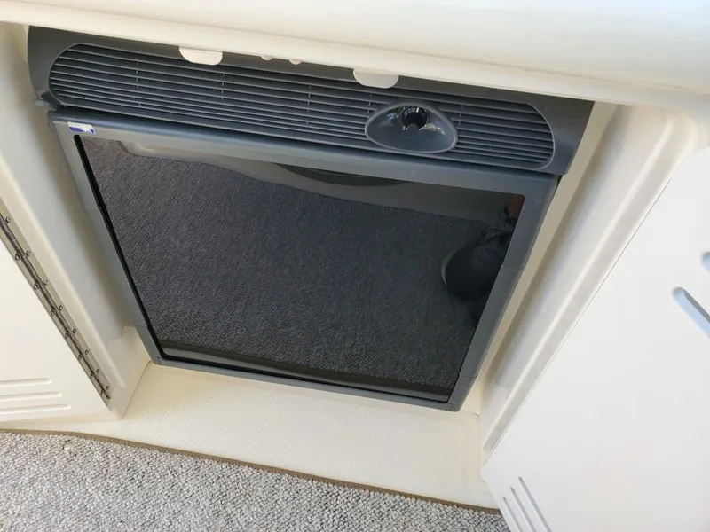 Slide: The Image of A small refrigerator is integrated into the boat's galley, surrounded by white cabinetry. - 22