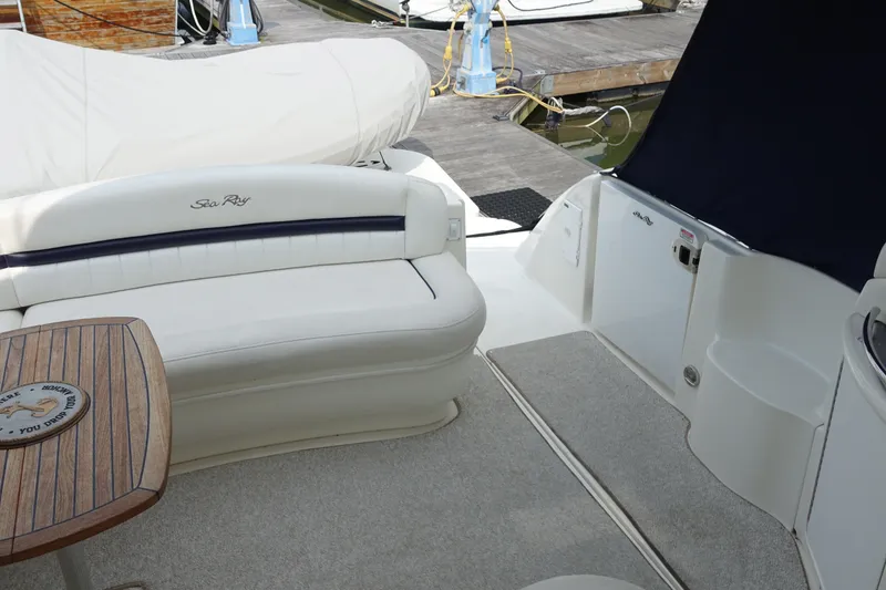 Slide: The Image of 2006 Sea Ray 44 Sundancer yacht interior with seating and wooden table at dock. - 21