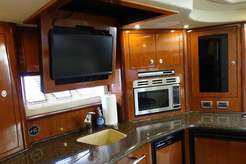 Slide: The Image of Luxurious 2006 Sea Ray 44 Sundancer yacht kitchen with TV, microwave, and elegant wood cabinetry. - 27