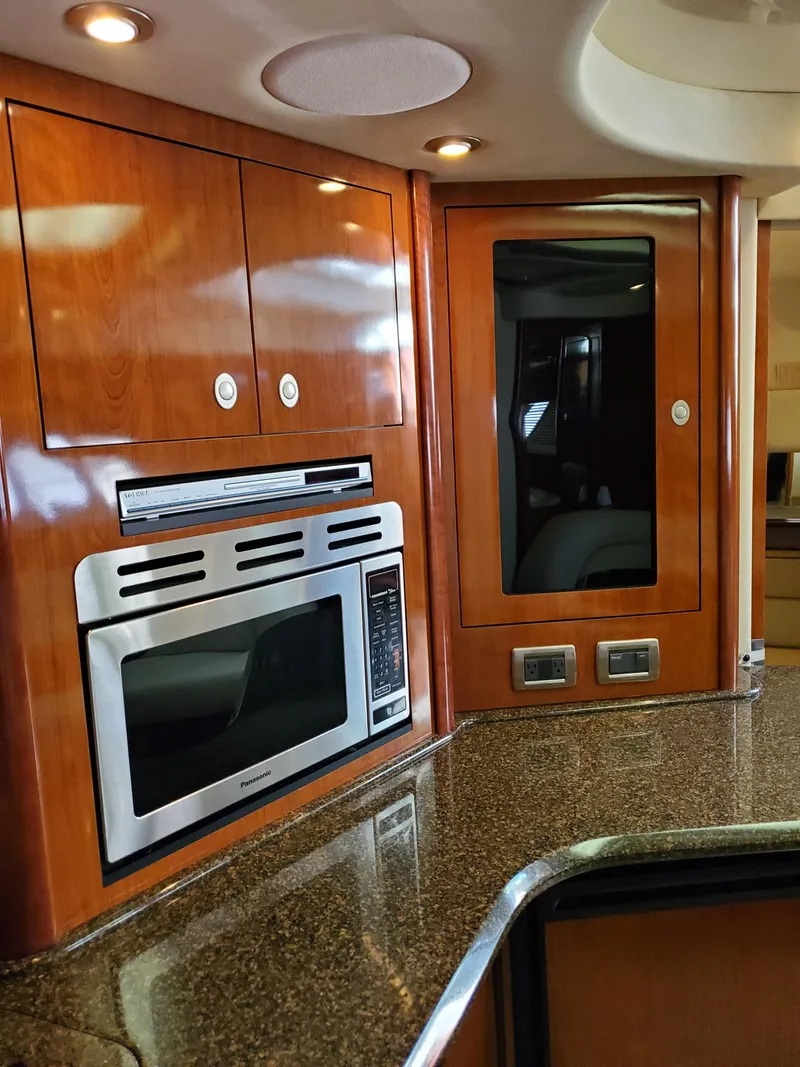 Slide: The Image of The 2006 Sea Ray 44 Sundancer's galley features wooden cabinets and a microwave. - 30