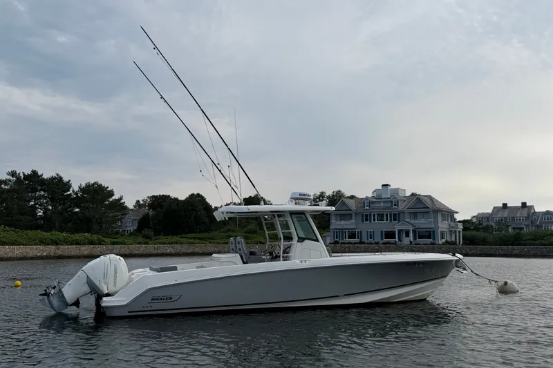 The Image of 2023 Boston Whaler 330 Outrage boat on calm water near waterfront homes. - 0