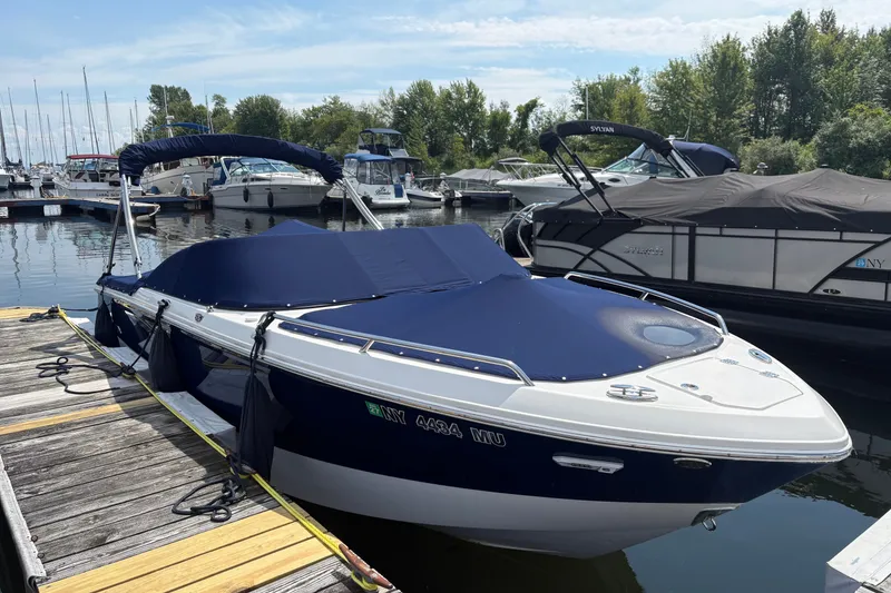 Slide: The Image of 2024 Chaparral 247 SSX boat docked at marina with blue cover. - 0