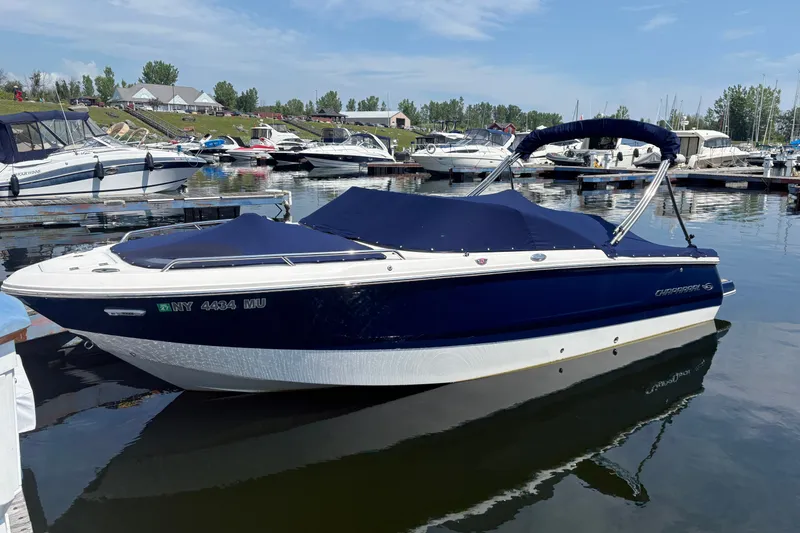 The Image of 2024 Chaparral 247 SSX boat docked in a marina, featuring a sleek blue and white design. - 1