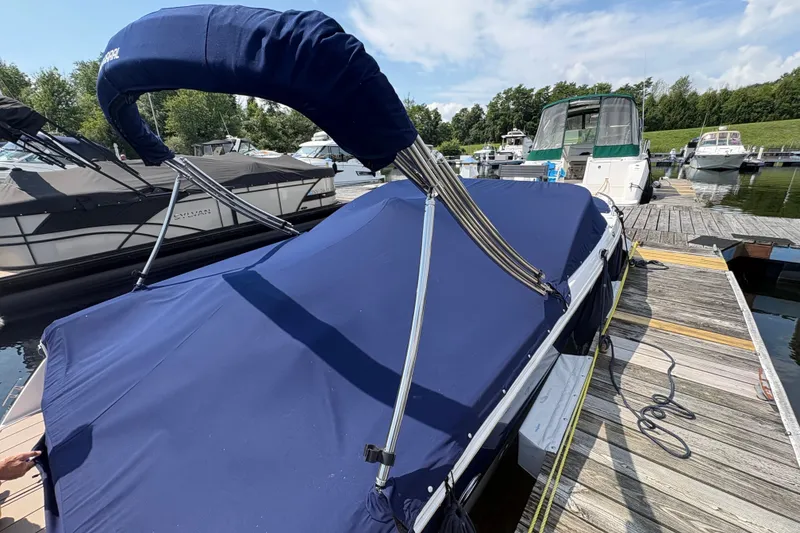 Slide: The Image of 2024 Chaparral 247 SSX boat docked with blue cover and canopy. - 2