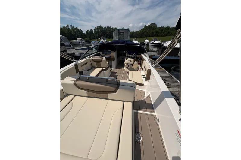 Slide: The Image of 2024 Chaparral 247 SSX boat interior with beige seating and sleek design at a marina. - 22