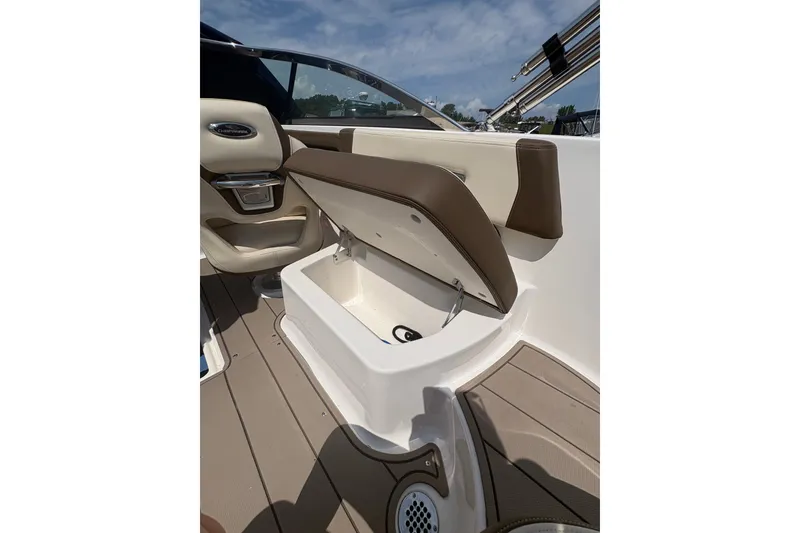 Slide: The Image of 2024 Chaparral 247 SSX boat interior with open storage compartment, beige and brown seating. - 17