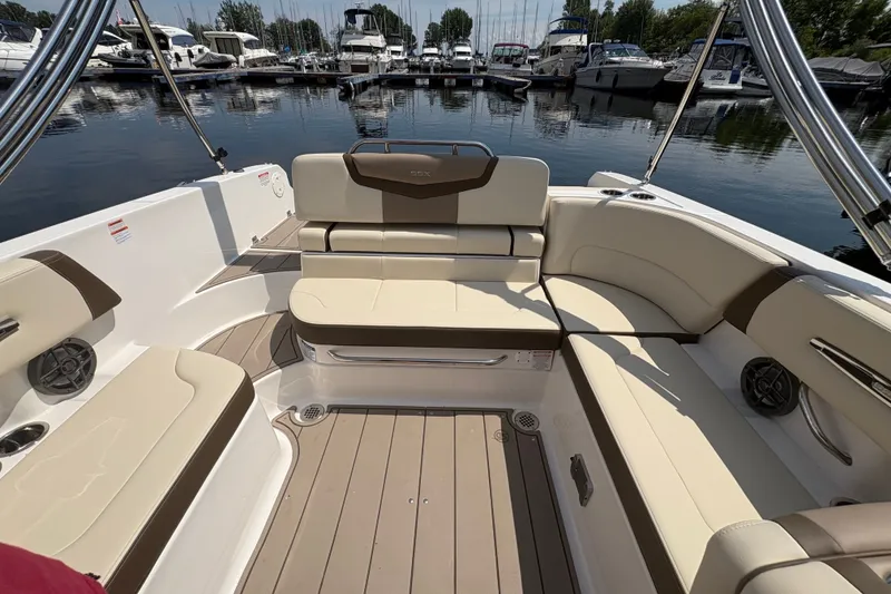 Slide: The Image of 2024 Chaparral 247 SSX boat interior with beige seating and sleek design at a marina. - 19