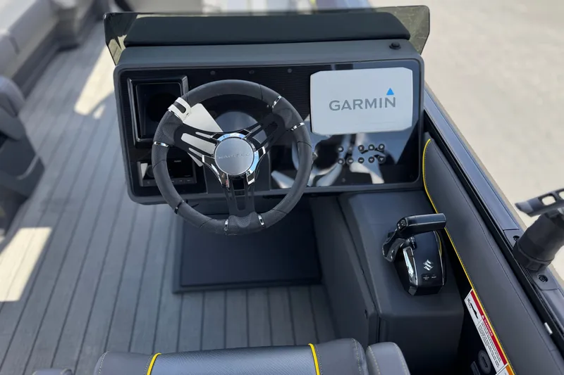 Slide: The Image of 2025 Manitou EXPLORE 24 boat dashboard with Garmin navigation system and steering wheel. - 26
