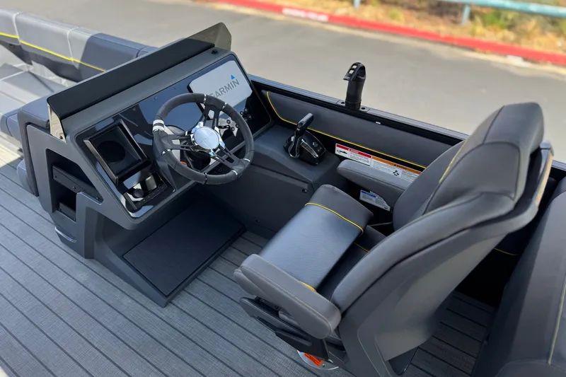 Slide: The Image of 2025 Manitou EXPLORE 24 boat cockpit with steering wheel and seating, featuring Garmin technology. - 25
