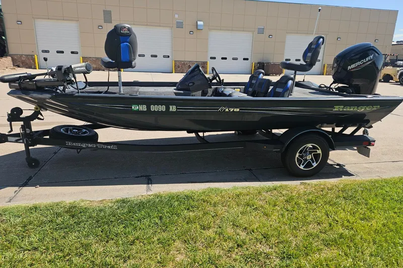 The Image of 2023 Ranger RT178 fishing boat on trailer, parked outdoors near industrial building. - 0