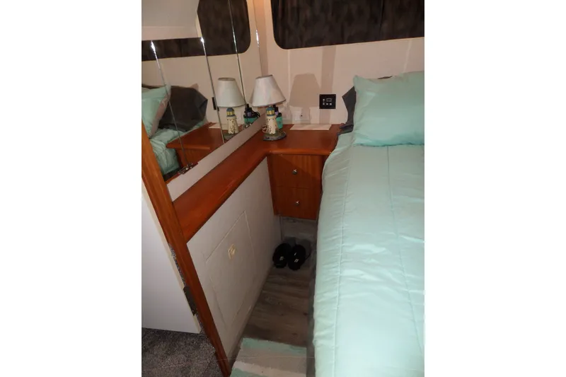 Slide: The Image of 1994 Silverton 34 Aft Cabin Motor Yacht bedroom with teal bedding and wooden cabinetry. - 60