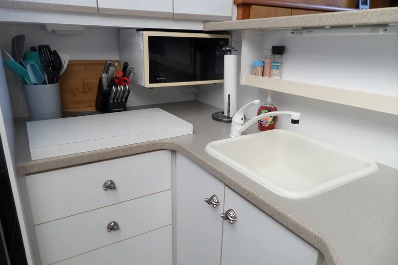Slide: The Image of Compact kitchen in a 1994 Silverton 34 Aft Cabin Motor Yacht with sink, microwave, and utensils. - 36