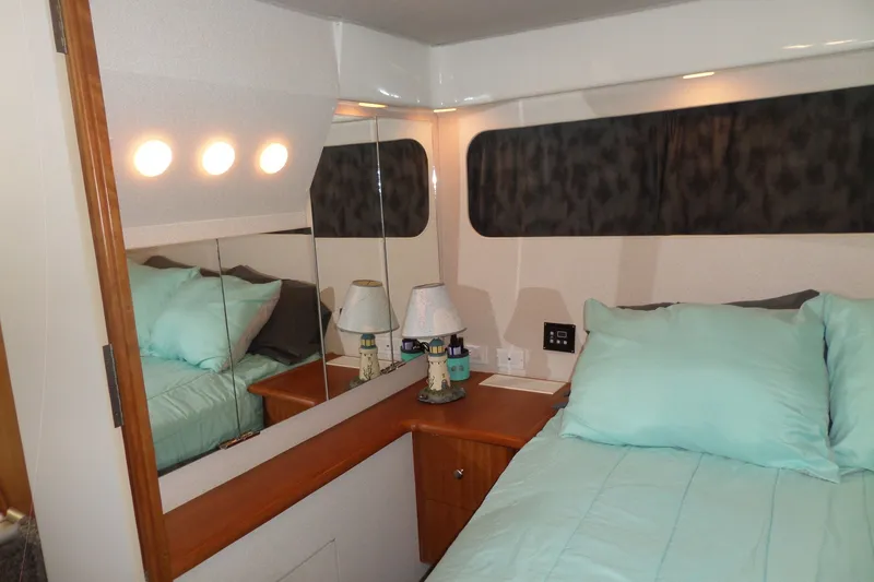 Slide: The Image of Cozy bedroom in 1994 Silverton 34 Aft Cabin Motor Yacht with teal bedding and wooden accents. - 59