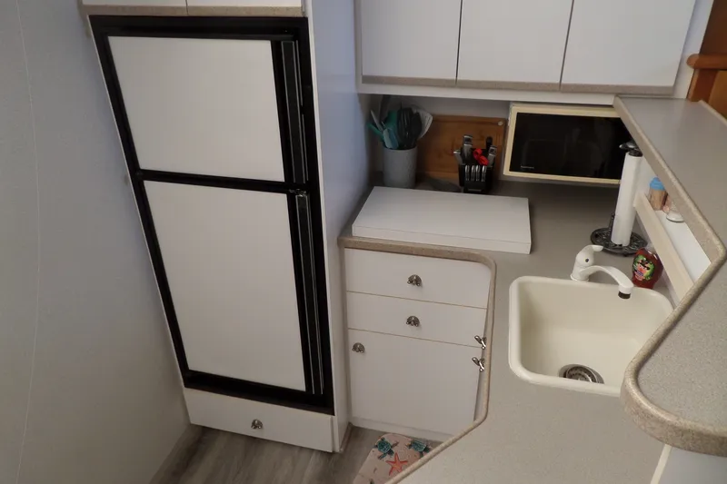 Slide: The Image of Compact kitchen in a 1994 Silverton 34 Aft Cabin Motor Yacht with sink, fridge, and microwave. - 33