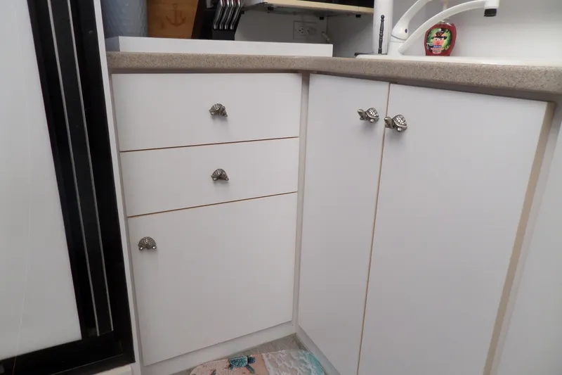 Slide: The Image of White kitchen cabinets with decorative knobs in a 1994 Silverton 34 Aft Cabin Motor Yacht. - 35