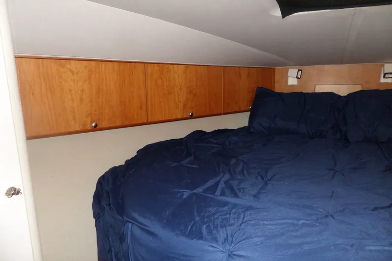 Slide: The Image of 1994 Silverton 34 Aft Cabin Motor Yacht bedroom with blue bedding and wooden cabinets. - 48