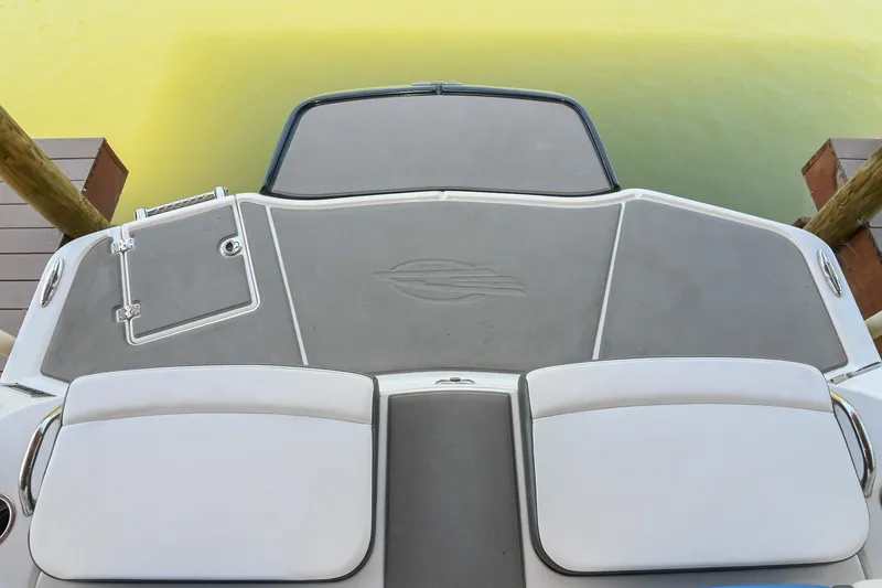Slide: The Image of 2019 Chaparral Vortex 2430 VRX boat deck with logo, docked by green water. - 12