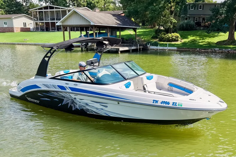 Slide: The Image of 2019 Chaparral 203 Vortex boat cruising on a lake near a dock and houses. - 1