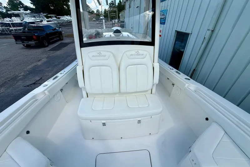 Slide: The Image of 2021 Regulator 26XO boat interior with white seating and console, parked near a building. - 6