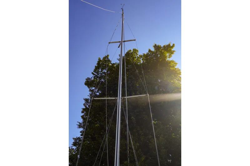 Slide: The Image of Mast of a 1990 Ericson 32.5 sailboat against a clear blue sky and trees. - 24