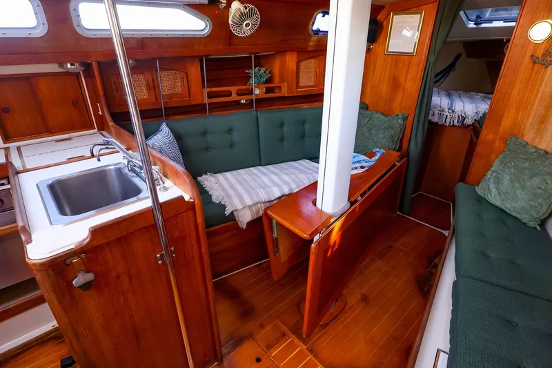 Slide: The Image of Cozy interior of a 1990 Ericson 32.5 sailboat with wooden finishes and green cushions. - 26