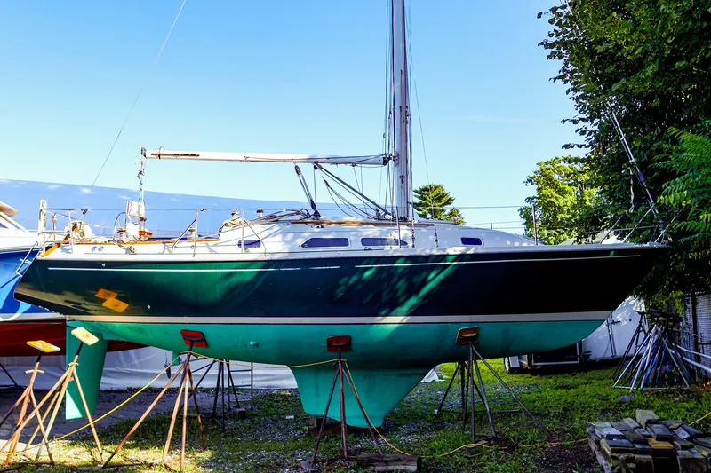 The Image of 1990 Ericson 32.5 sailboat on stands, outdoor storage, vibrant green hull. - 1