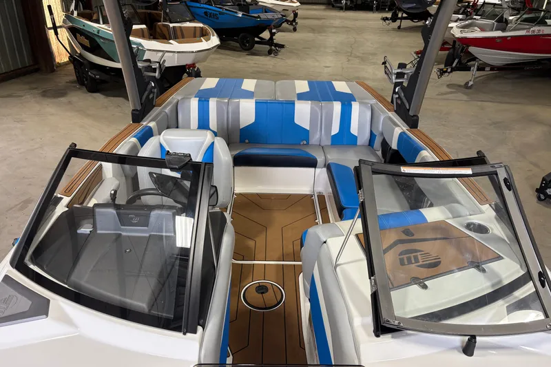 Slide: The Image of 2023 Malibu Wakesetter 21 LX boat interior with blue and gray seating in a showroom. - 1