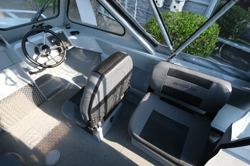 Slide: The Image of Interior of 2026 Hewescraft 180 Sportsman boat, featuring steering wheel and seating. - 11