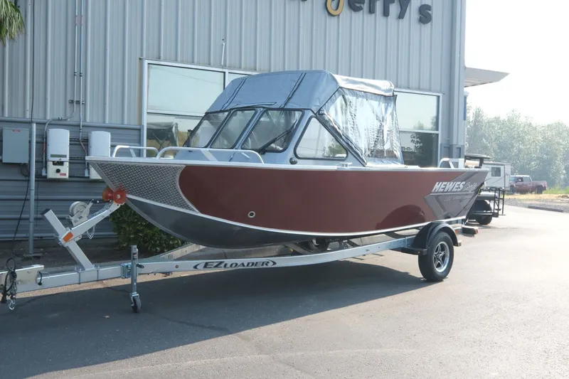 The Image of 2026 Hewescraft 180 Sportsman boat on trailer outside a building. - 2
