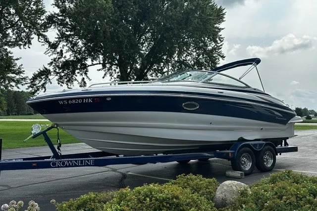 Slide: The Image of 2007 Crownline 260 LS boat on trailer, parked outdoors with trees in background. - 2
