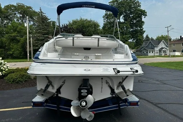 Slide: The Image of 2007 Crownline 260 LS boat, rear view, parked on asphalt with trees and houses in background. - 4