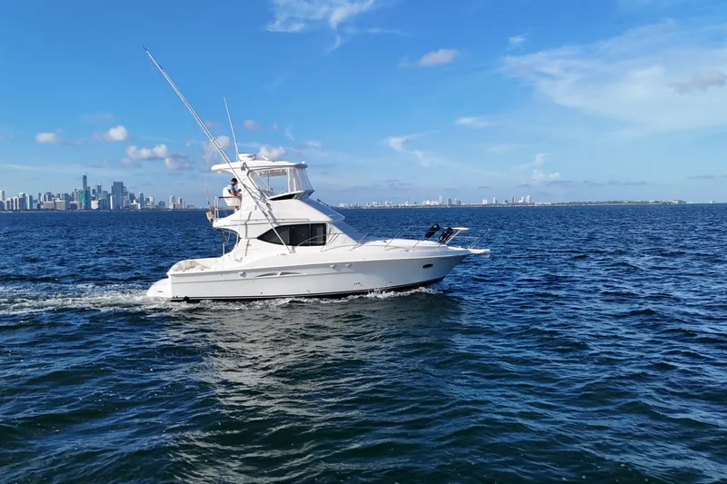 The Image of 2007 Silverton 38 Convertible yacht cruising on open water with city skyline backdrop. - 0