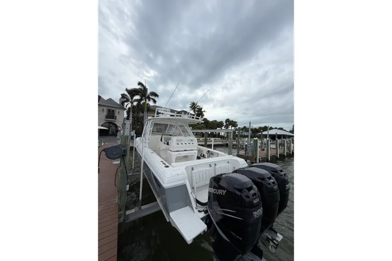 Slide: The Image of 2010 Intrepid 370 Cuddy boat docked with triple Mercury engines, under cloudy sky. - 4