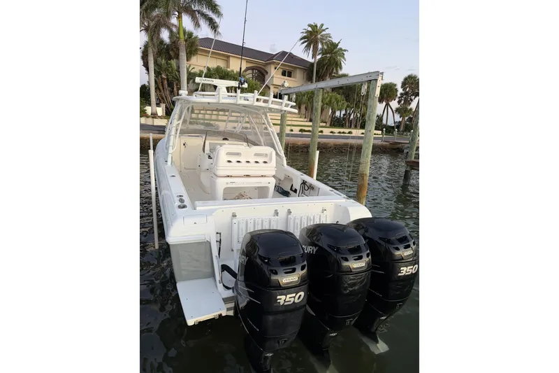 Slide: The Image of 2010 Intrepid 370 Cuddy boat with triple Mercury 350 engines docked by palm trees. - 11