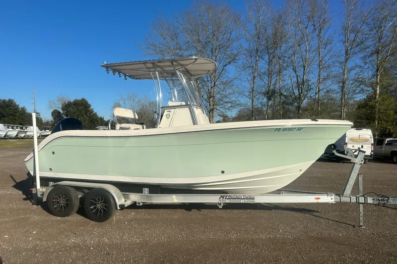 Slide: The Image of 2021 Cobia 220 Center Console boat on trailer, parked outdoors under clear blue sky. - 2