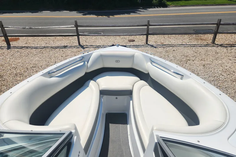 Slide: The Image of 2012 Cobalt 220 boat interior with white seating, parked near a road. - 8