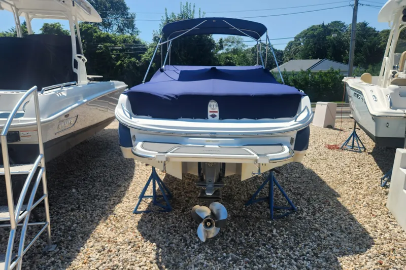 Slide: The Image of 2012 Cobalt 220 boat with blue cover on gravel lot, surrounded by other boats. - 2