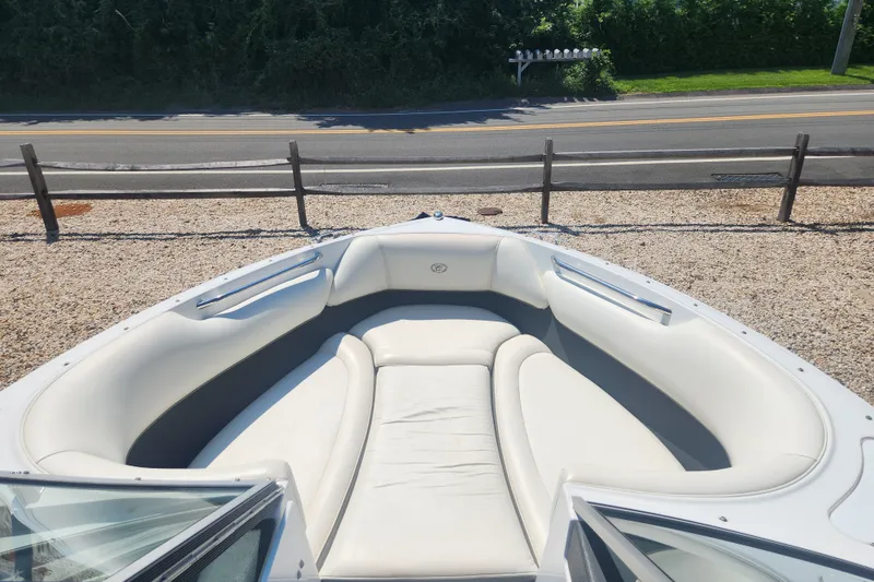 Slide: The Image of 2012 Cobalt 220 boat with white cushioned seating, parked near a road and fence. - 9