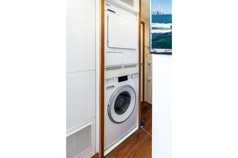 Slide: The Image of Laundry area inside 2019 Sunseeker 86 Yacht, featuring a stacked washer and dryer. - 136