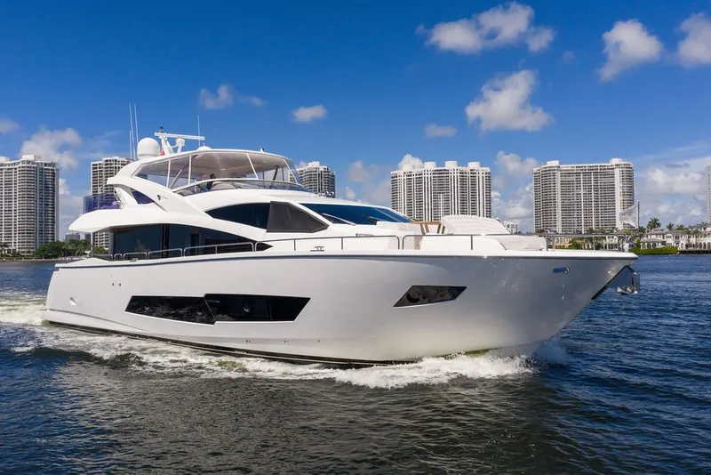 Slide: The Image of Luxurious 2019 Sunseeker 86 Yacht cruising near waterfront skyscrapers under a clear blue sky. - 25