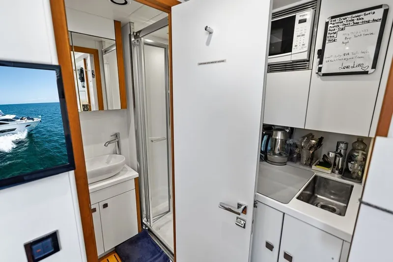 Slide: The Image of Interior of a 2019 Sunseeker 86 Yacht featuring a compact kitchen and bathroom. - 133