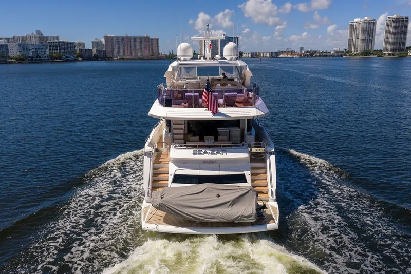 Slide: The Image of 2019 Sunseeker 86 Yacht cruising on a sunny day, city skyline in background. - 19