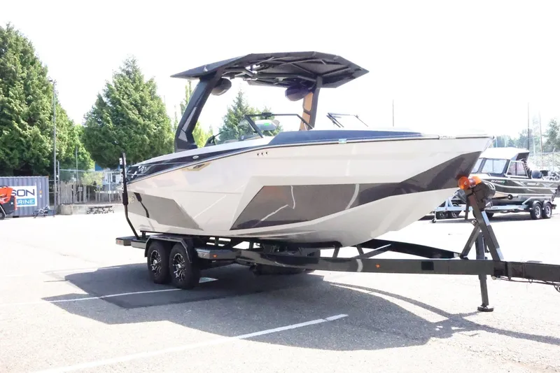 Slide: The Image of A modern 2027 Tigé Z3 on a trailer, surrounded by trees and other boats. - 6