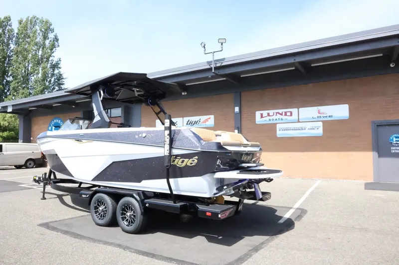 Slide: The Image of A 2027 Tigé Z3 boat on a trailer in front of a building with several signs. - 13