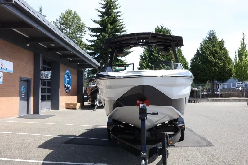 Slide: The Image of A 2027 Tigé Z3 boat on a trailer in front of a building, with trees in the background. - 5
