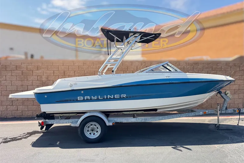 The Image of 2012 Bayliner 195 Bowrider boat on trailer, blue and white design, parked outdoors. - 0