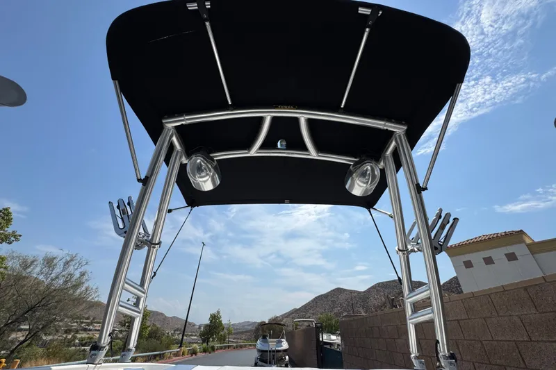 Slide: The Image of 2012 Bayliner 195 Bowrider with a black bimini top and stainless steel frame. - 13