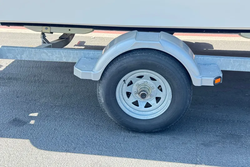 Slide: The Image of Trailer wheel of a 2012 Bayliner 195 Bowrider on asphalt pavement. - 26